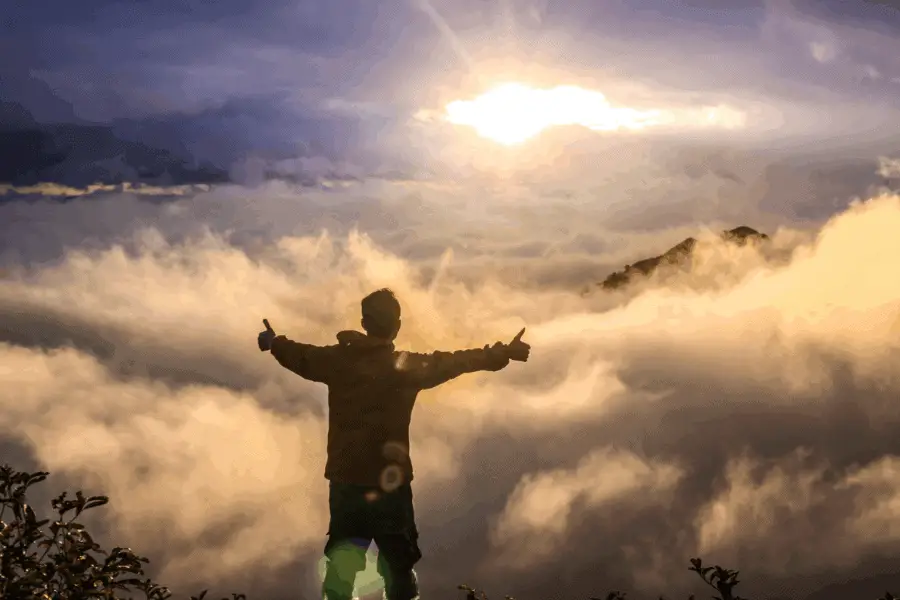 Excited Guy On Top Of Mountain With Sunlight And Clouds