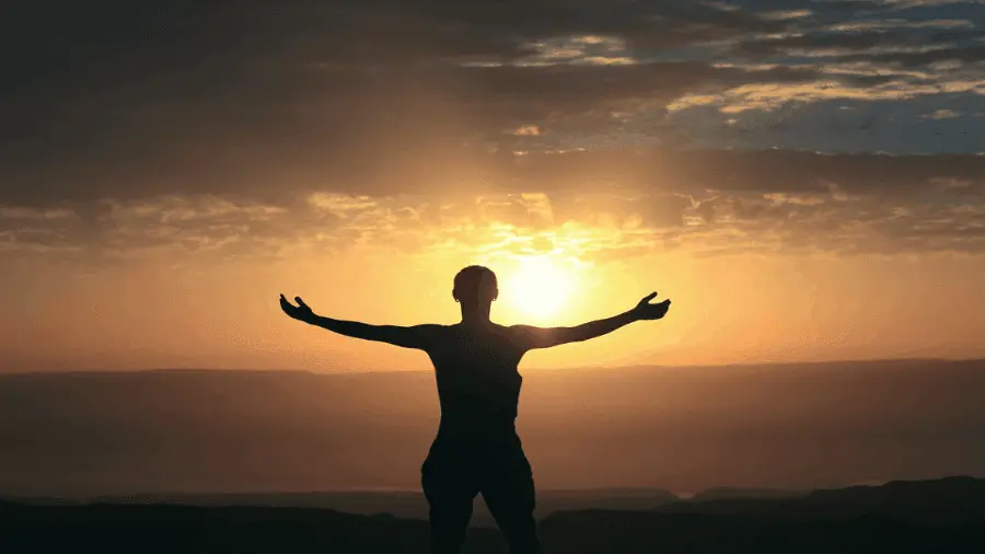 Person Standing Arms Open Towards Sun