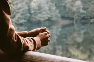 Persons Hands Waiting Patiently On Balcony Overseeing Trees And Lake