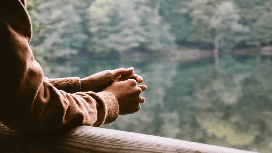 Persons Hands Waiting Patiently On Balcony Overseeing Trees And Lake 900x506