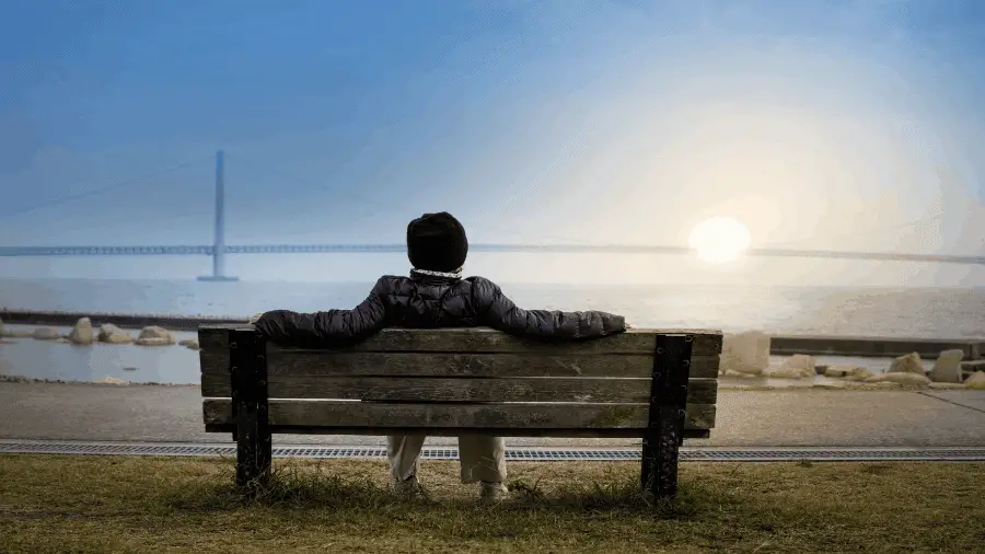 Person Resting On Bench Near Ocean 900x506